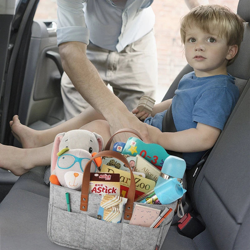 Gray Baby Felt Organizer Bag Filled With Baby Items In A Car With A Kid Traveling