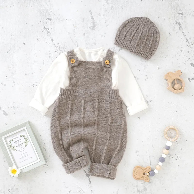 Dark Khaki Baby Knitted Romper with Hat laid in a white marble background with toys and frame props