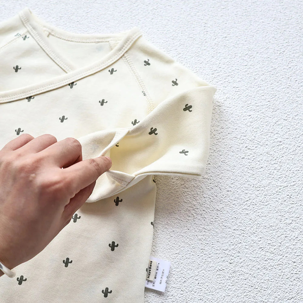 A closeup photo showing the Baby's cactus Printed White long sleeve bodysuit's handcuff's pocket