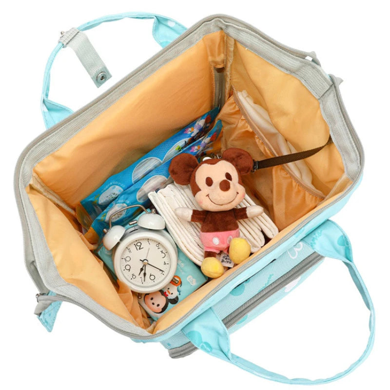 Open suitcase with a toy, books, clothes, and an alarm clock, viewed from above.
