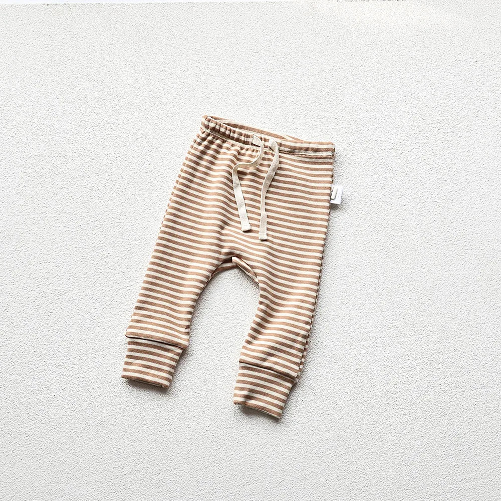 Brown and white striped baby pajama pants in a light gray background