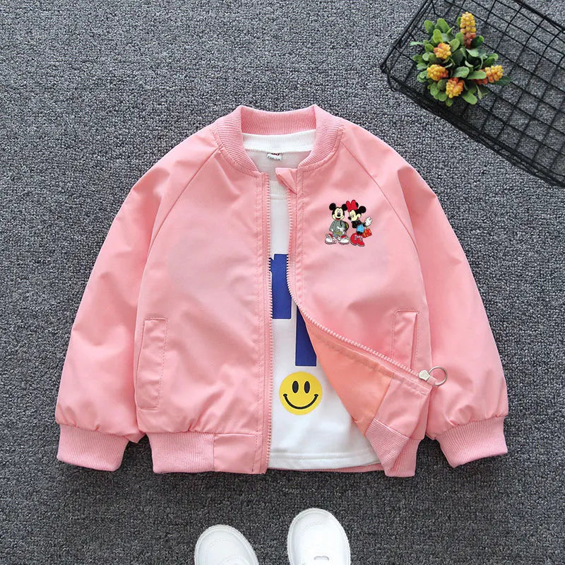 Pink Mickey Mouse Design Printed Toddler Bomber Jacket Laid In a Gray Background With Basket Prop and White Shoes