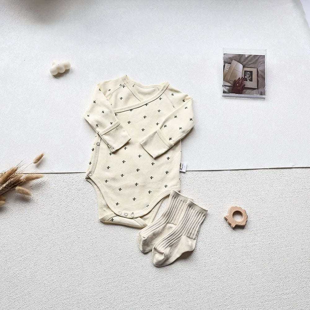 Cactus Printed White long sleeve baby bodysuit with white socks in an aesthetic light gray background
