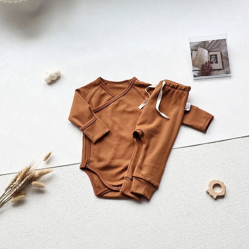 Brown baby long sleeve bodysuit and pants set in an aesthetic light gray background