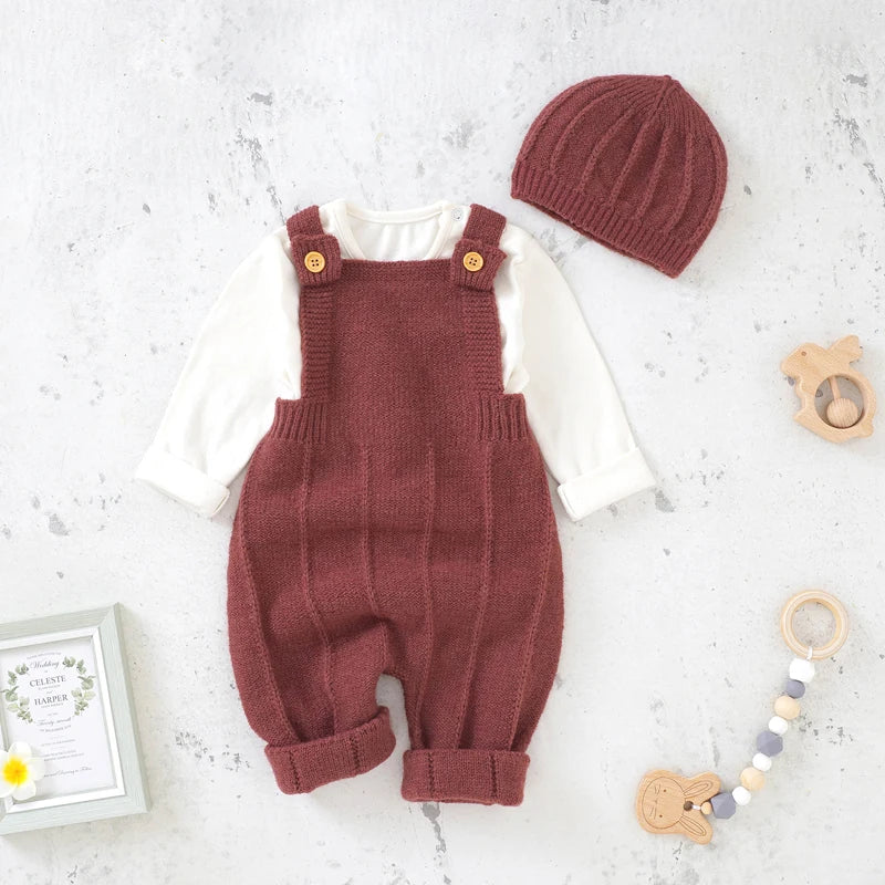 Rose Red Baby Knitted Romper with Hat laid in a white marble background with toys and frame props