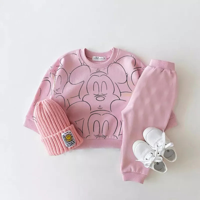 Pink mickey mouse printed tracksuit set with long sleeve pullover shirt, pink solid color pants, pink beanie with white shoes in a gray background