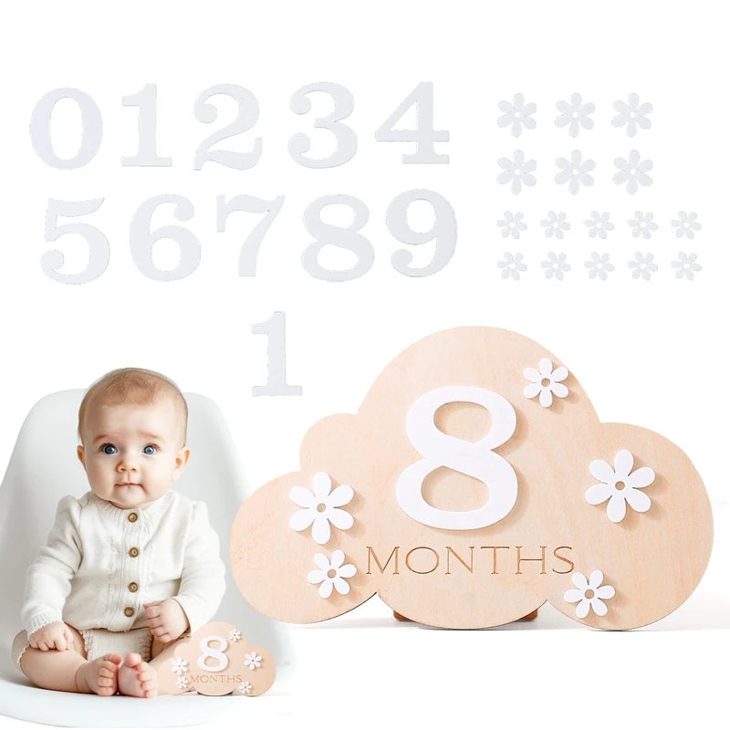 Cloud shaped baby wooden monthly milestone set with a baby sitting in the corner in a white background