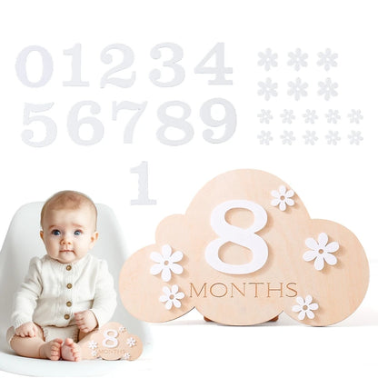 Cloud shaped baby wooden monthly milestone set with a baby sitting in the corner in a white background