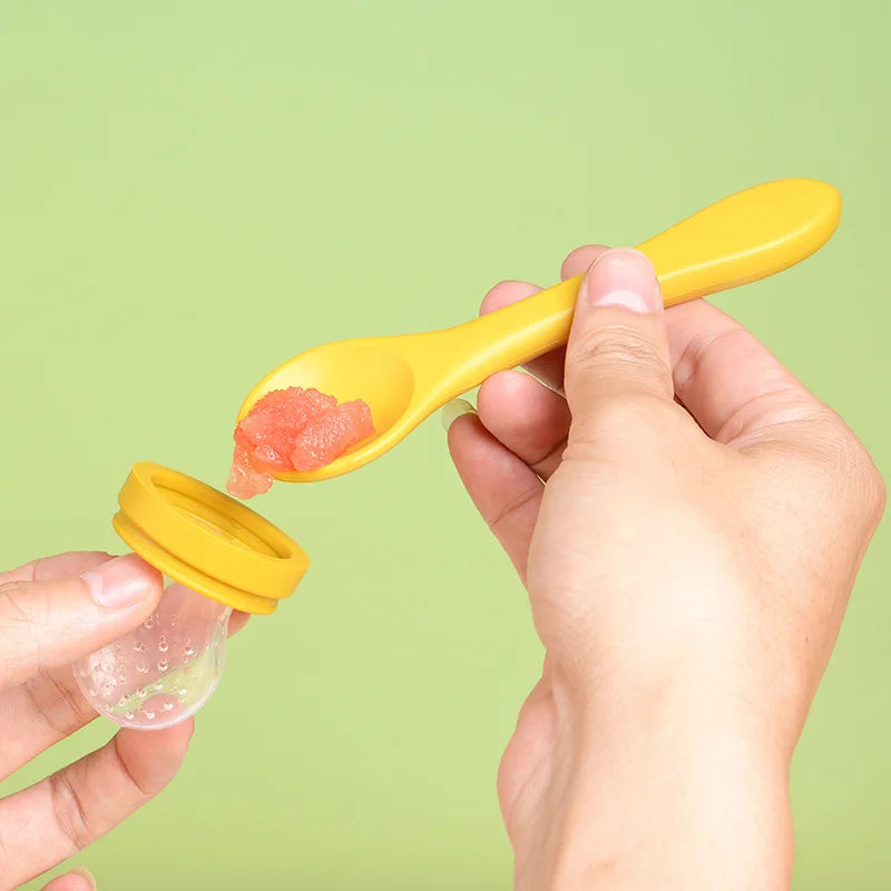 Hands holding a yellow spoon scooping baby food from a jar against a green background.