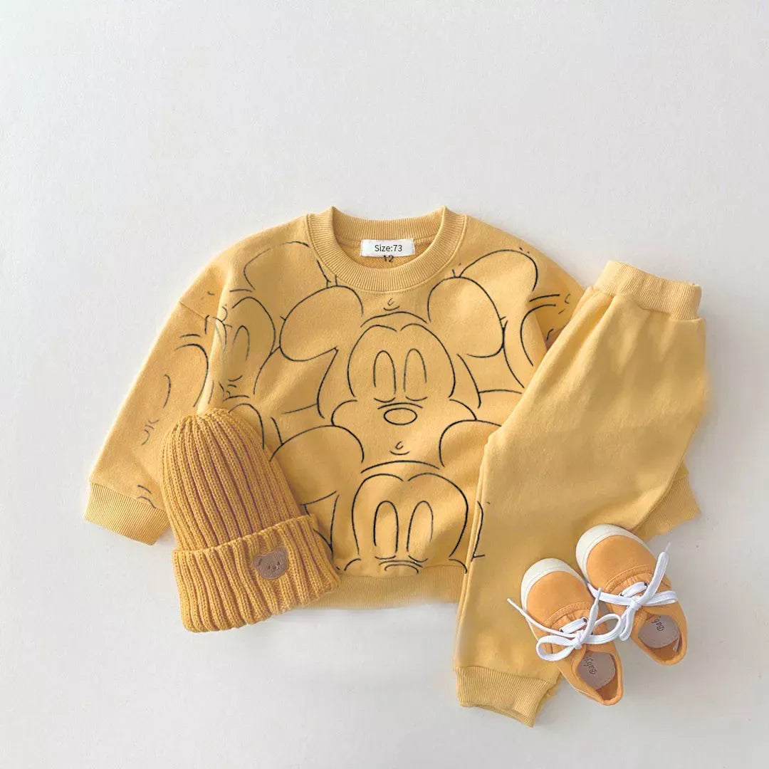 Yellow mickey mouse printed tracksuit set with long sleeve pullover shirt, yellow solid color pants, yellow beanie with yellow shoes in a gray background