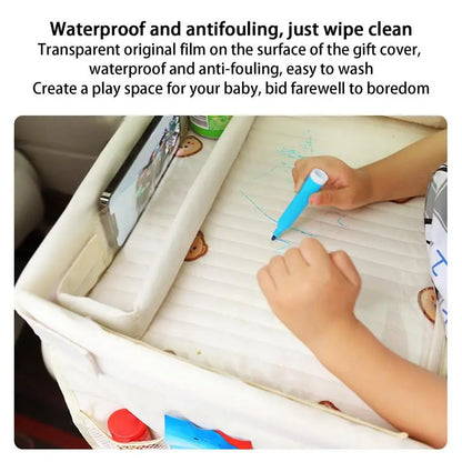 Child's hands drawing on a waterproof play mat with a marker, with a tablet visible.
