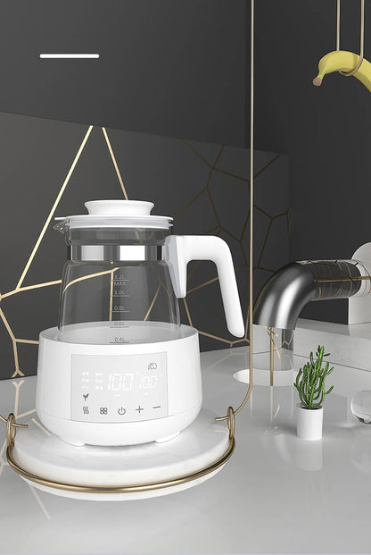Modern kitchen with an electric kettle on a white base, black tiled backsplash with gold accents, and a potted plant.