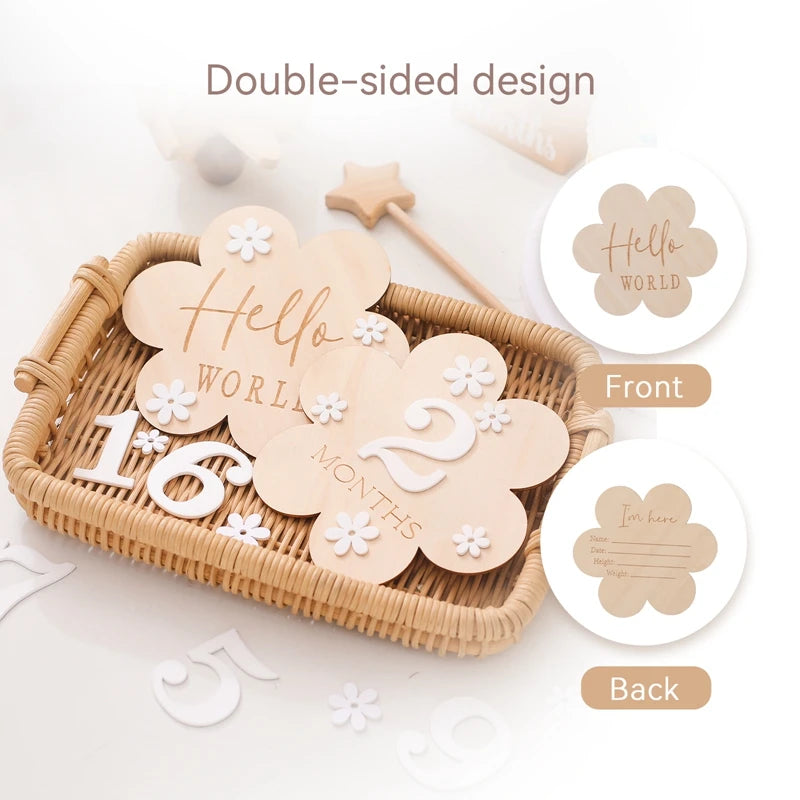 A flower shaped wooden milestone card displaying Hello World alongside another card displaying 2 months, in a rattan tray, highlighting double sided design
