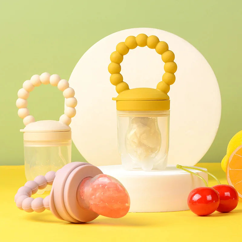 Baby teething toys and a silicone feeder on a green and yellow background.