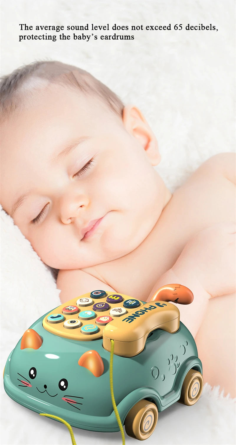 A child's toy phone in the shape of a green cat with colorful buttons on a soft surface.