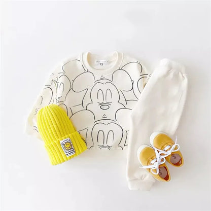 White mickey mouse printed tracksuit set with long sleeve pullover shirt, white solid color pants, white beanie with yellow shoes in a gray background